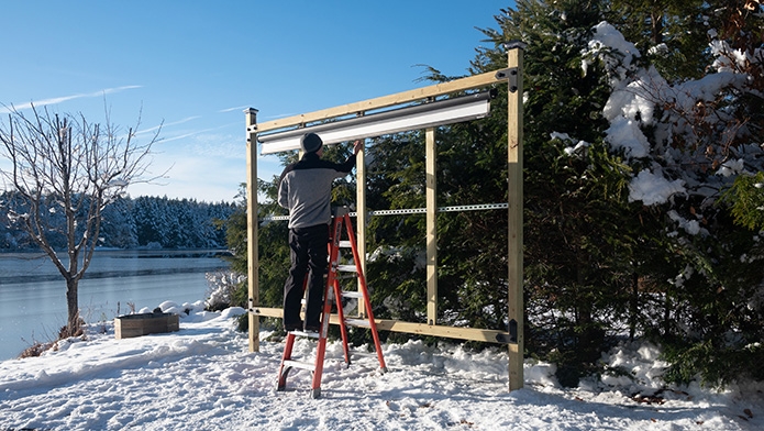 Todd Morton, founder of the Wireless Outdoor Cinema hanging an outdoor projector screen on a Timberline Outdoor Movie Theater.